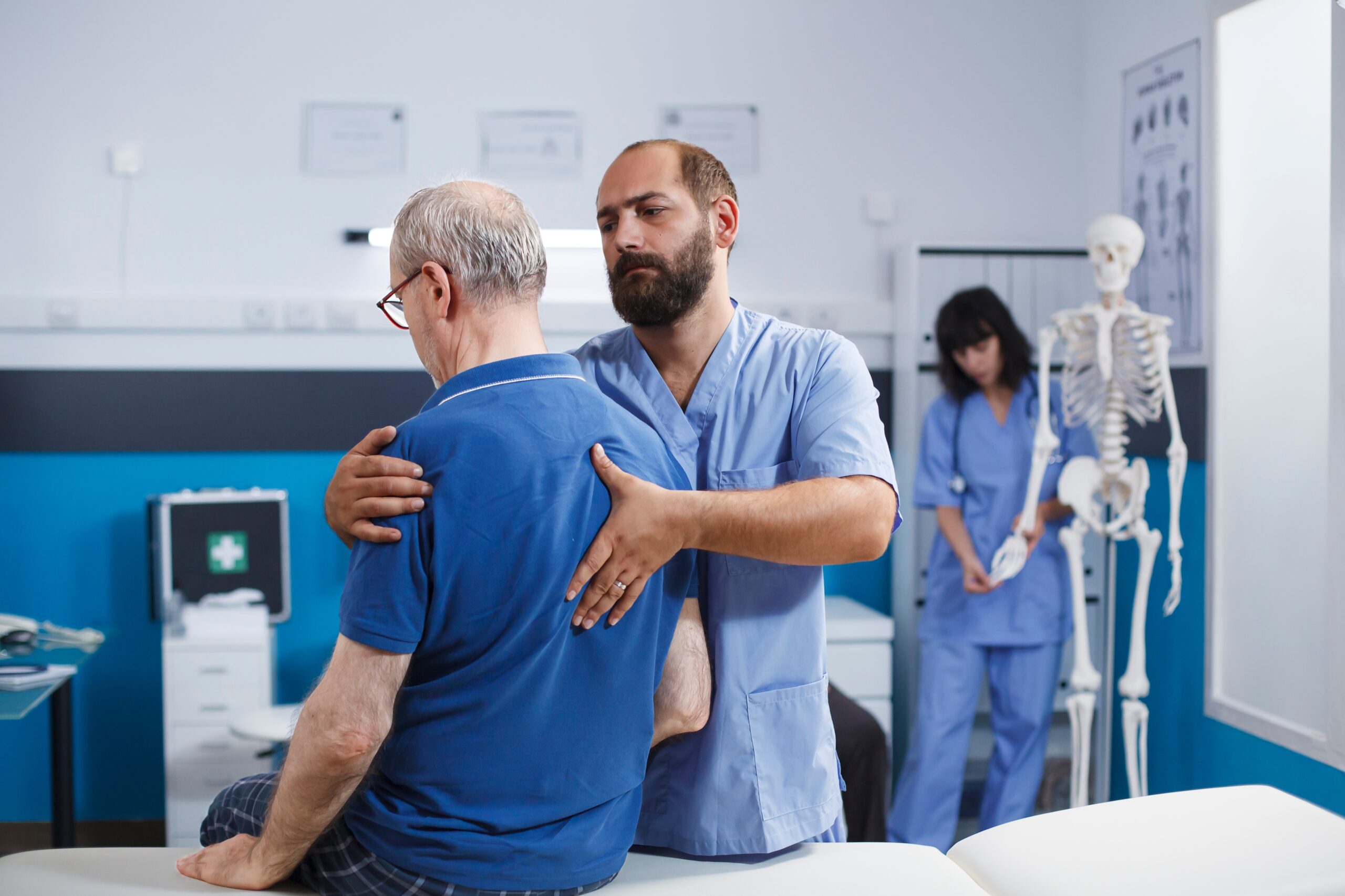 A male doctor physically inspecting a male patient to determine the proper back spine pain treatment option for them.