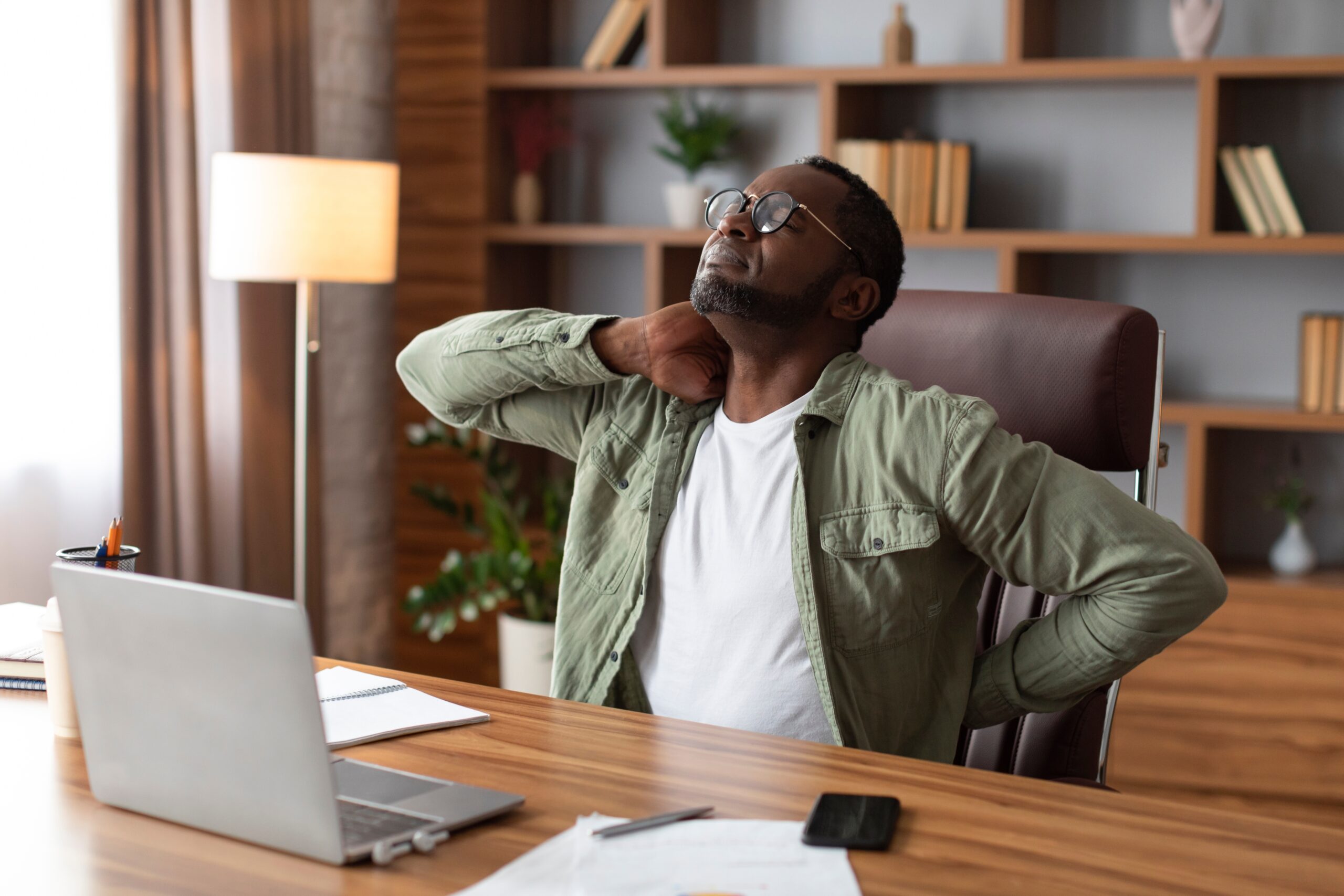 A worker at a desk, managing back pain.